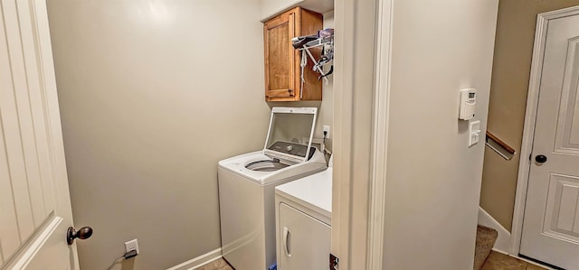 clothes washing area featuring baseboards, cabinet space, and washer and clothes dryer