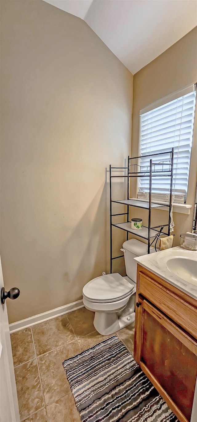 bathroom with tile patterned flooring, vaulted ceiling, vanity, baseboards, and toilet