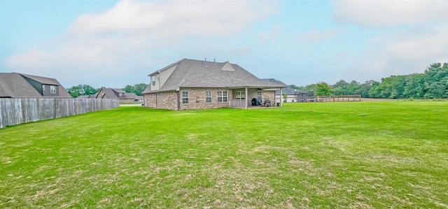 rear view of house with a lawn and fence