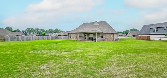 rear view of property featuring a lawn, cooling unit, a fenced backyard, and a patio area