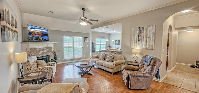 living room with baseboards, arched walkways, ceiling fan, and wood finished floors