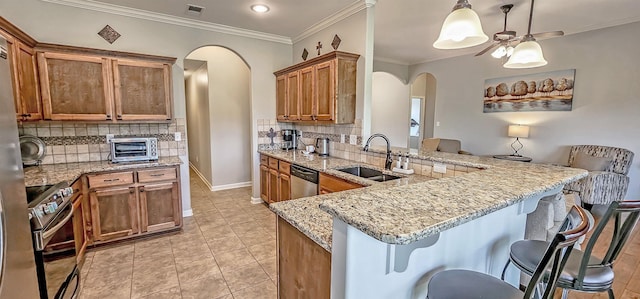 kitchen featuring visible vents, arched walkways, tasteful backsplash, appliances with stainless steel finishes, and brown cabinets