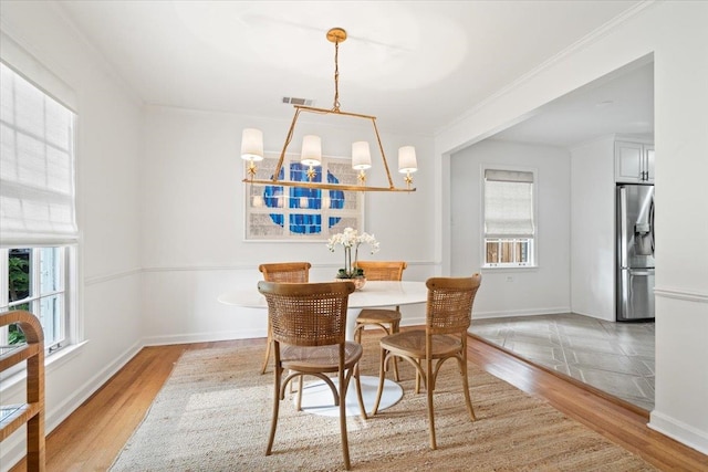 dining area with plenty of natural light, light wood-style floors, baseboards, and an inviting chandelier