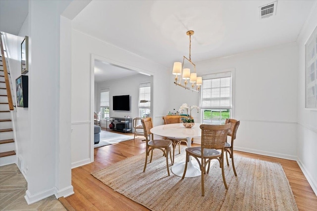 dining space featuring a notable chandelier, light wood-style floors, baseboards, visible vents, and stairway