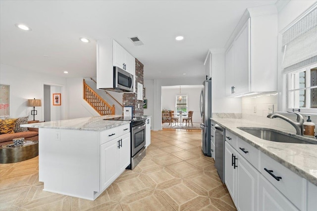 kitchen with visible vents, appliances with stainless steel finishes, light stone countertops, a sink, and white cabinets