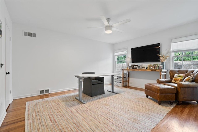 home office with a ceiling fan, visible vents, plenty of natural light, and wood finished floors