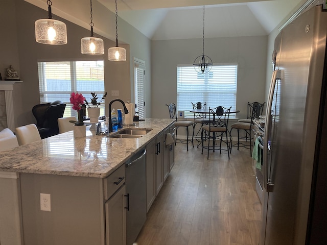 kitchen with white cabinets, appliances with stainless steel finishes, a sink, lofted ceiling, and light wood-type flooring