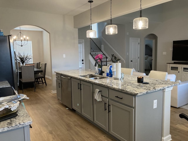 kitchen featuring stainless steel appliances, arched walkways, a sink, and light wood-type flooring