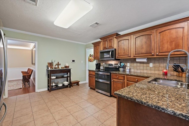 kitchen with visible vents, crown molding, a sink, backsplash, and stainless steel appliances
