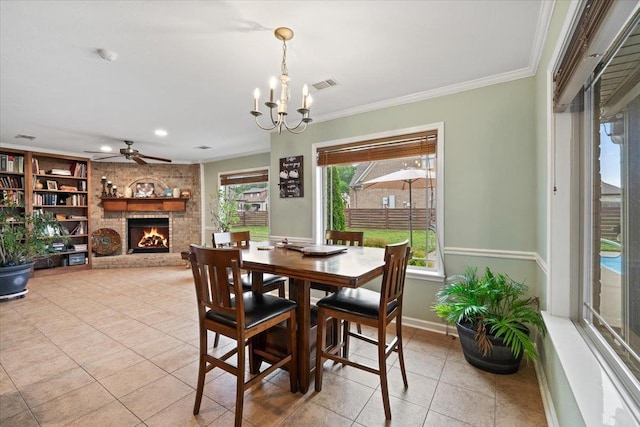 dining room with visible vents, crown molding, light tile patterned flooring, a fireplace, and ceiling fan with notable chandelier