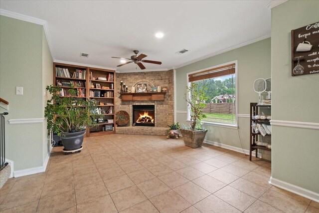 living room with crown molding, ceiling fan, a fireplace, baseboards, and visible vents
