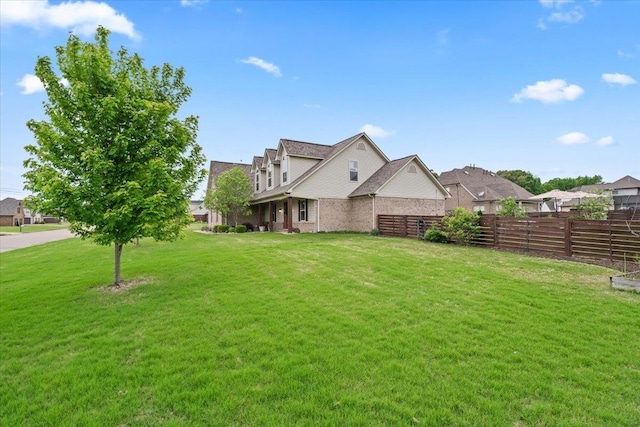 exterior space featuring fence, a front lawn, and brick siding