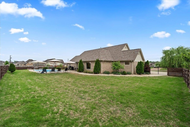 exterior space with fence private yard, a patio, brick siding, a fenced in pool, and a lawn
