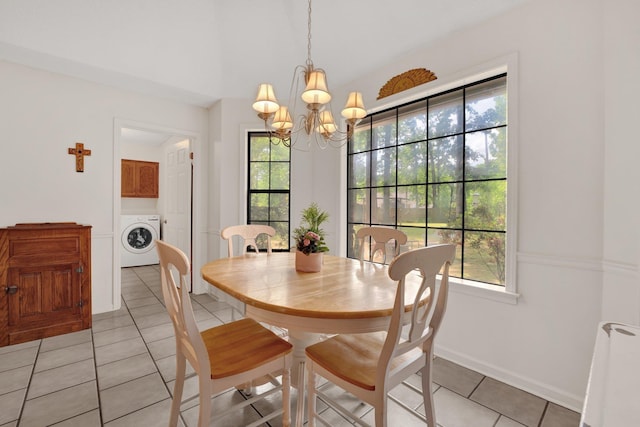 dining area featuring an inviting chandelier, baseboards, washer / dryer, and light tile patterned floors