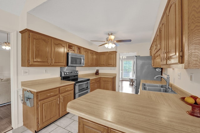 kitchen with ceiling fan, a sink, light countertops, a peninsula, and stainless steel appliances