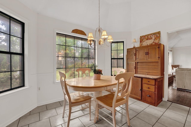 dining room featuring an inviting chandelier, vaulted ceiling, light tile patterned flooring, and a healthy amount of sunlight
