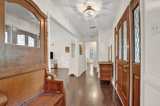 entrance foyer featuring visible vents, ornamental molding, wainscoting, a decorative wall, and dark wood finished floors