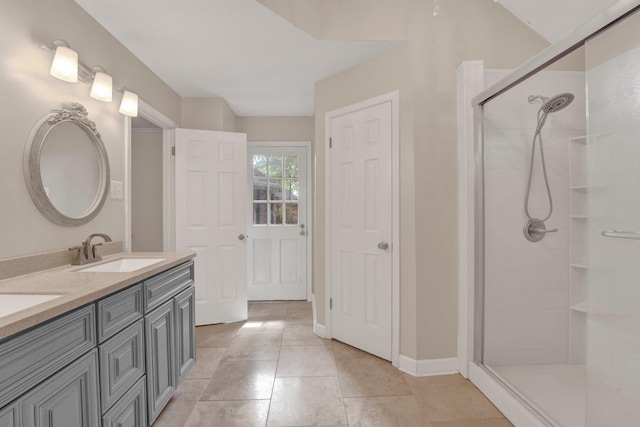 bathroom with a sink, tile patterned floors, double vanity, and tiled shower
