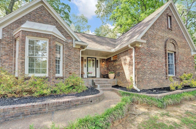 view of front facade featuring brick siding and roof with shingles