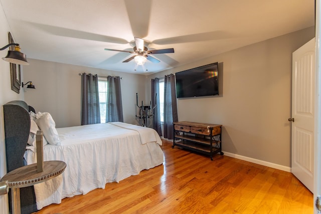 bedroom featuring baseboards, light wood finished floors, and ceiling fan
