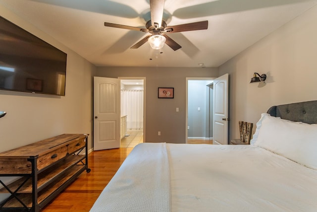 bedroom with baseboards, ceiling fan, wood finished floors, and ensuite bathroom