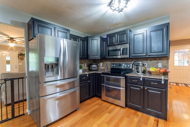 kitchen with appliances with stainless steel finishes, tasteful backsplash, and light wood finished floors