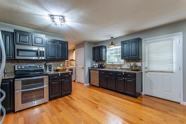 kitchen featuring backsplash, stainless steel appliances, a sink, and light wood finished floors