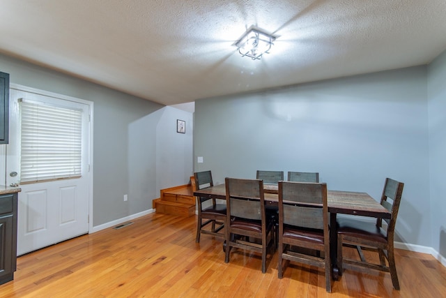 dining space with visible vents, light wood-style floors, and baseboards