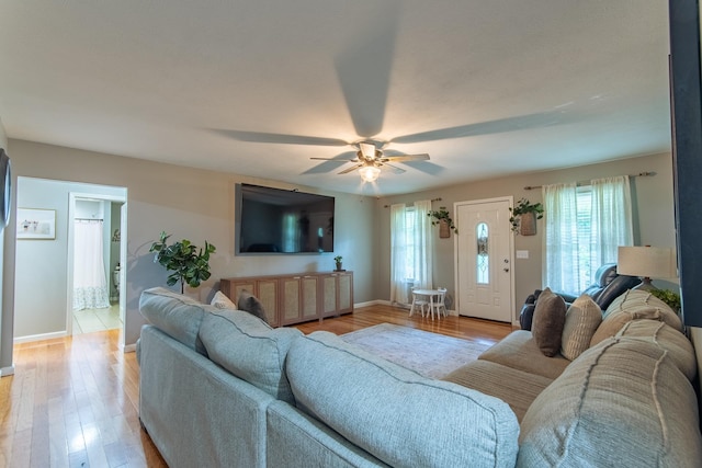 living area with baseboards, ceiling fan, and light wood finished floors