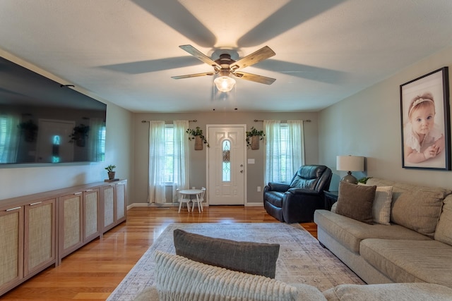 living room with a ceiling fan, baseboards, and light wood-style floors