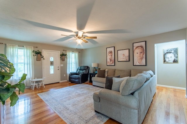 living room with baseboards, ceiling fan, and light wood-style flooring