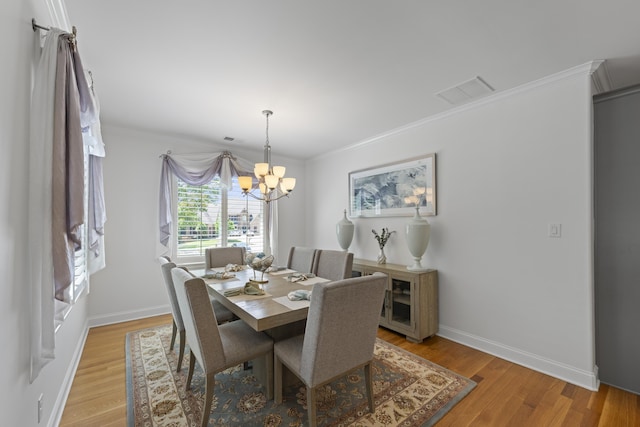 dining space featuring light wood-style floors, visible vents, baseboards, an inviting chandelier, and ornamental molding
