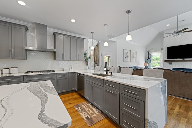 kitchen with a sink, gray cabinets, a peninsula, and wall chimney exhaust hood