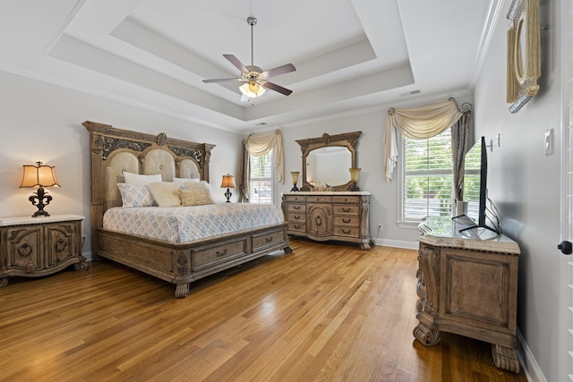 bedroom featuring a ceiling fan, visible vents, a raised ceiling, baseboards, and light wood-style flooring