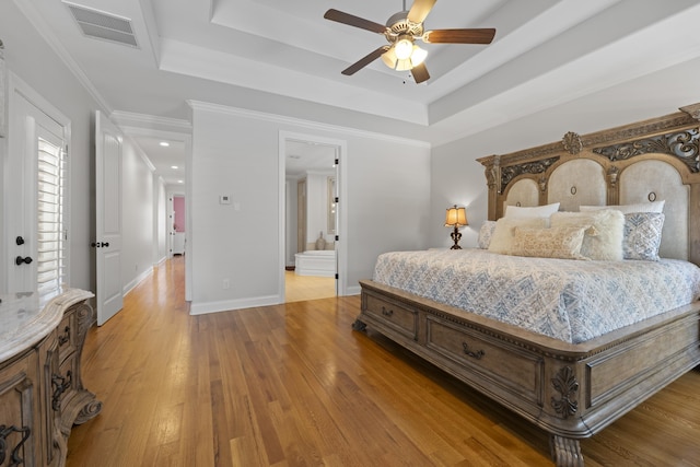 bedroom featuring light wood-style floors, a raised ceiling, baseboards, and visible vents