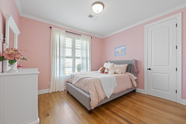 bedroom with crown molding, baseboards, visible vents, and light wood-style floors