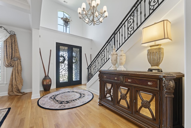 entryway with an inviting chandelier, a towering ceiling, wood finished floors, baseboards, and stairway
