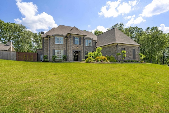 french country home with brick siding, a front lawn, and fence
