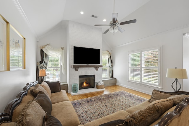 living room featuring a ceiling fan, a fireplace, vaulted ceiling, wood finished floors, and ornamental molding