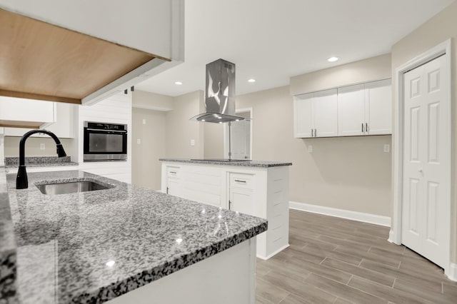1296 Monasco Rd, Millington, TN 38053 - kitchen with baseboards, wall oven, island range hood, white cabinetry, and a sink