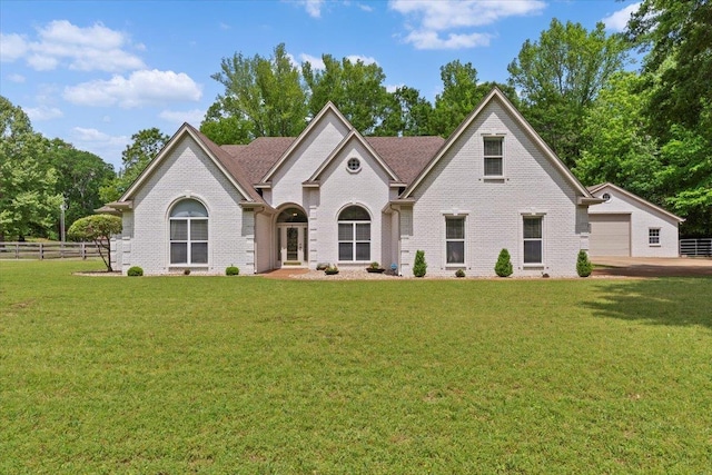 view of front of property featuring fence, a front yard, a garage, and brick siding