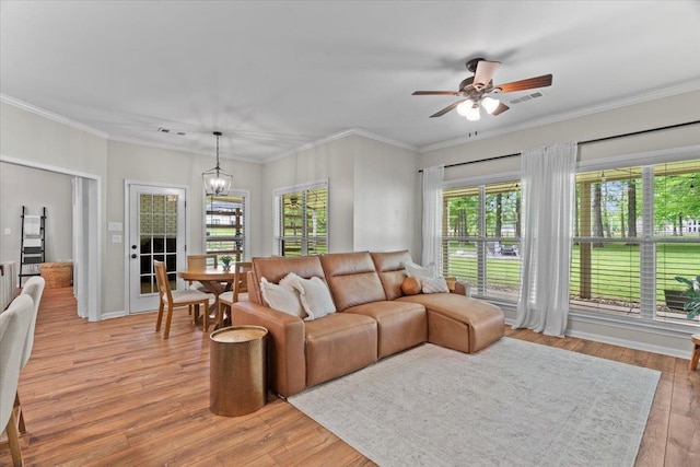 living room with crown molding, visible vents, light wood-style flooring, and ceiling fan with notable chandelier