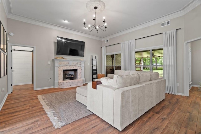 living room featuring a notable chandelier, a brick fireplace, baseboards, wood finished floors, and visible vents