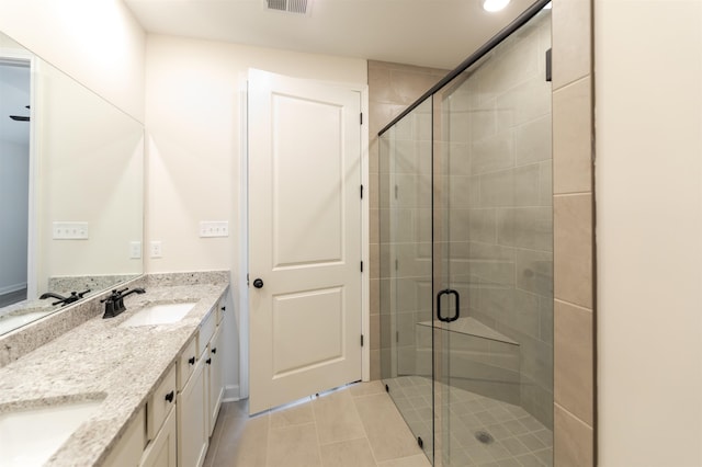 full bathroom with double vanity, a shower stall, a sink, and tile patterned flooring
