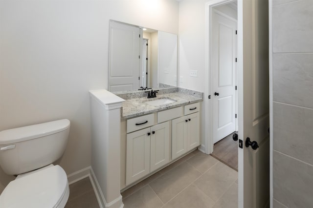 bathroom featuring vanity, baseboards, tile patterned floors, and toilet