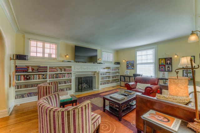 living area with crown molding, a fireplace, and wood finished floors