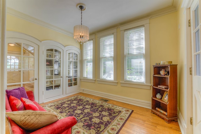 interior space featuring visible vents, baseboards, light wood finished floors, a notable chandelier, and ornamental molding