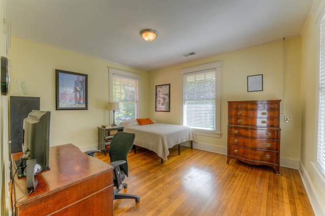 bedroom featuring baseboards, wood finished floors, and visible vents