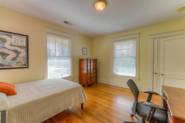 bedroom with baseboards, visible vents, multiple windows, and light wood-style flooring
