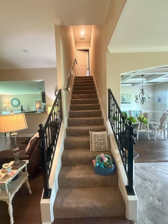 staircase featuring visible vents, ornamental molding, and a chandelier